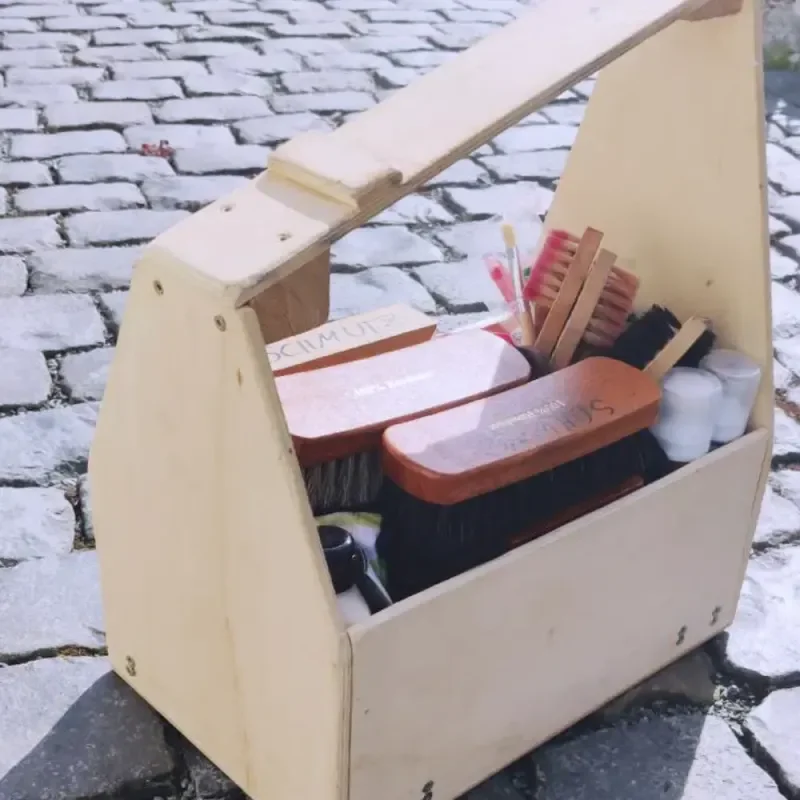Holzkiste mit Bürsten und Reinigungsmitteln auf Kopfsteinpflaster
