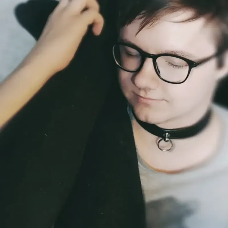 Person mit Brille und schwarzem Halsband blickt entspannt nach unten