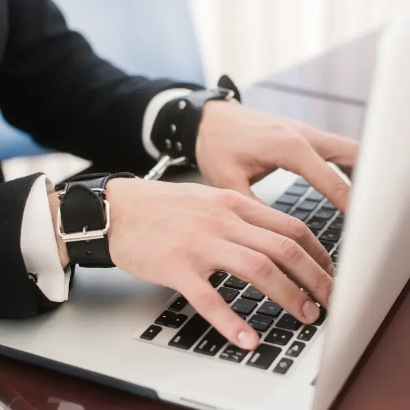 Hände mit schwarzen Manschetten tippen auf einer Laptop-Tastatur