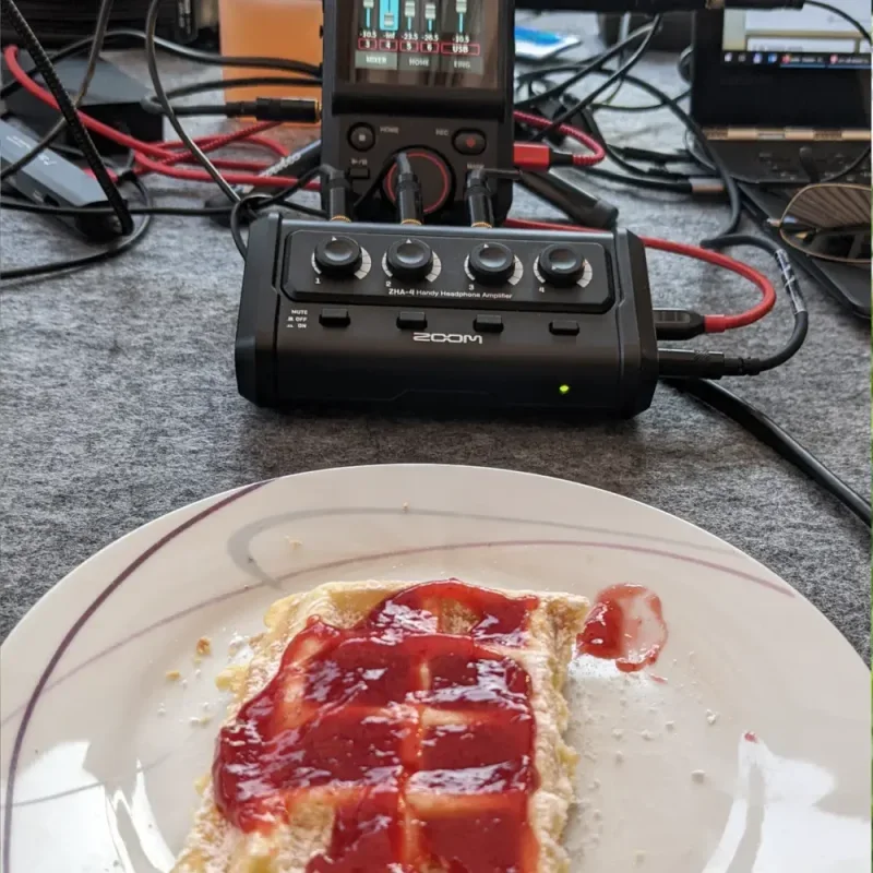 Waffel mit roter Marmelade auf einem Teller vor Podcast-Aufnahmegeräten und Kabeln