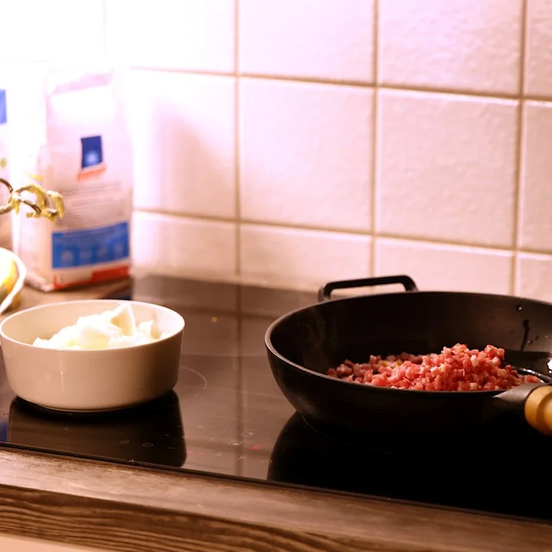 Schüssel mit Zwiebeln und Pfanne mit angebratenem Hackfleisch auf einer Küchenplatte
