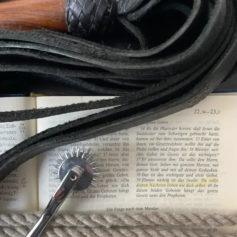Aufgeschlagene Bibel mit Peitsche und Dornenrad als Symbol für Daniel – Glaubhafter Konsens