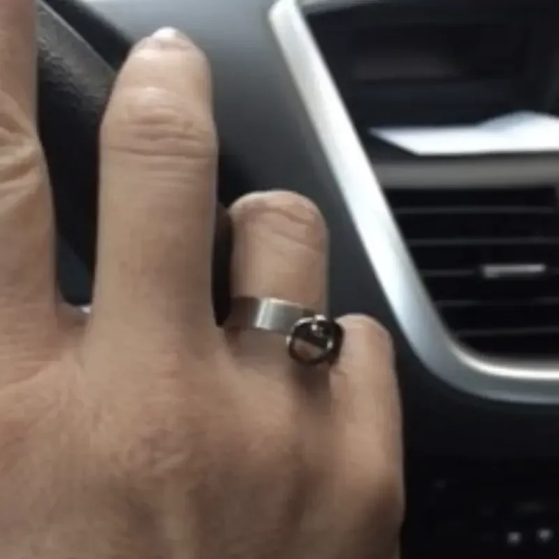 Hand mit Metallring am Finger vor dem Lüftungsgitter eines Autos