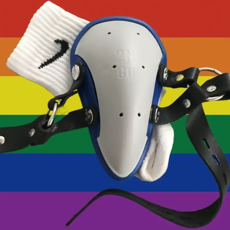 BDSM-Ausrüstung mit Tiefschutz, weißen Socken und Lederbändern vor Regenbogenflagge