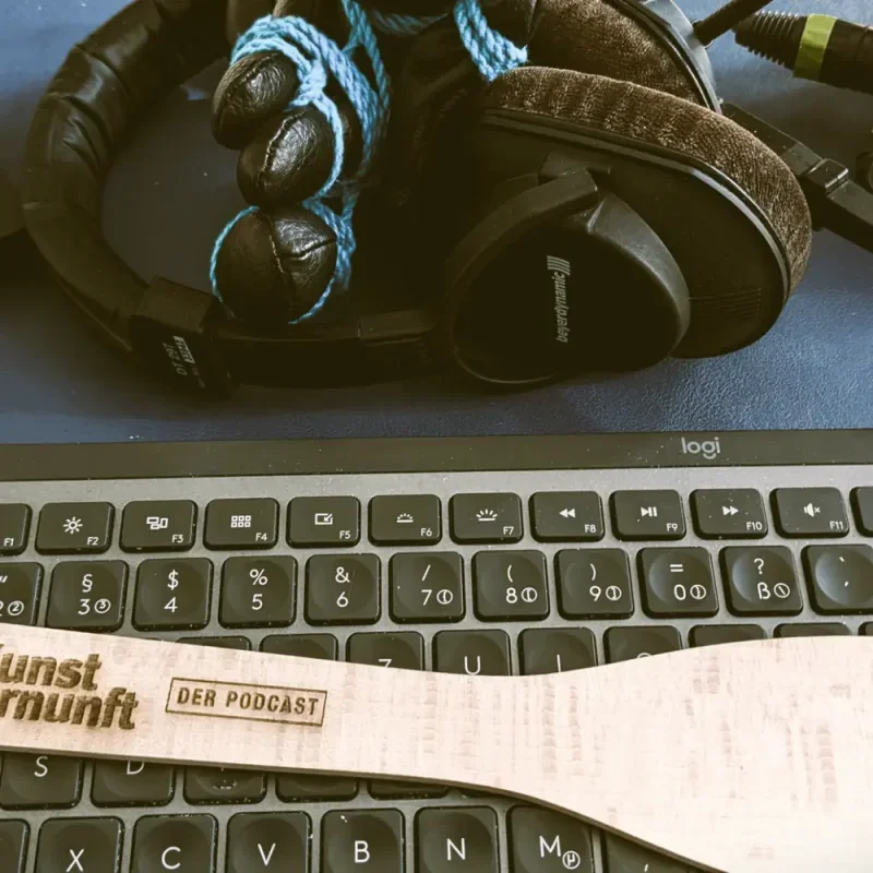 Kopfhörer mit blauem Seil auf einer Tastatur, daneben ein Streifen mit Unvernunft-Podcast-Logo