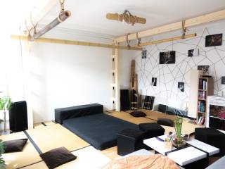 Helles Wohnzimmer mit Tatami-Matten, niedrigen Möbeln, Pflanzen und dekorativen Bambusrohren an der Decke.