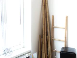 Bambusstäbe, eine Holzleiter und ein schwarzer Lautsprecher stehen in einer hellen Zimmerecke am Fenster.