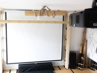 Heller Heimkinoraum mit Leinwand, Deckenprojektor, Lautsprechern und Holzbalken.